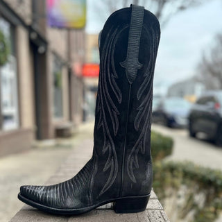 Black cowboy boot on a stone ledge with a city street background